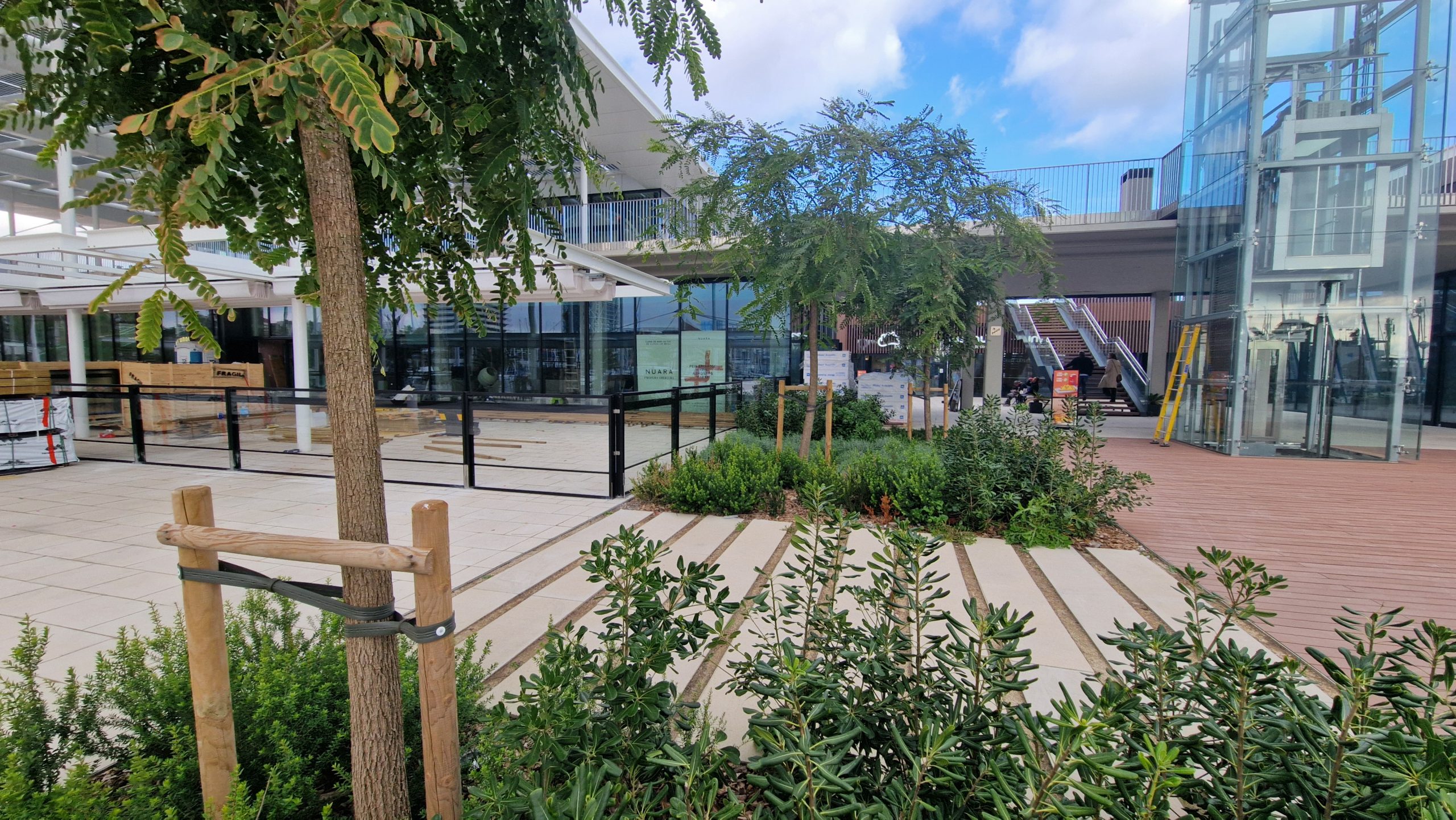 Espacio all aire libre con plantas y caminos de piedra. Hay velas de sombra en el fondo