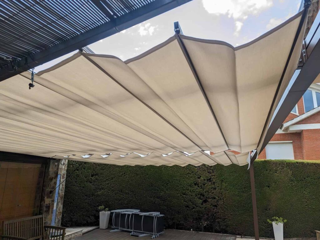 Pérgola con toldo corredero de lona beige extendido en la terraza de una vivienda en Viladecavalls.