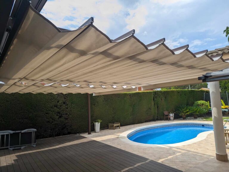 Pérgola con toldo corredero de ondas extendido sobre tarima exterior junto a la piscina en Viladecavalls.