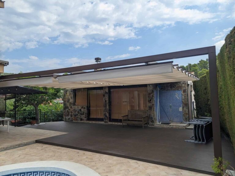 Pérgola de estructura oscura con toldo retráctil instalada sobre tarima exterior en una terraza con piscina en Viladecavalls.