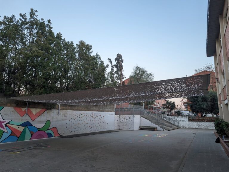 Malla de sombra tensada con diseño calado instalada sobre el patio de juegos de la Escola Josep Trueta en Viladecans.