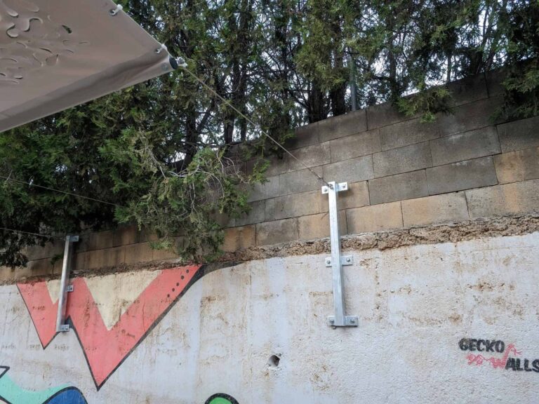 Detalle de los anclajes metálicos a muro y cables tensores para vela de sombra en la Escola Josep Trueta de Viladecans.