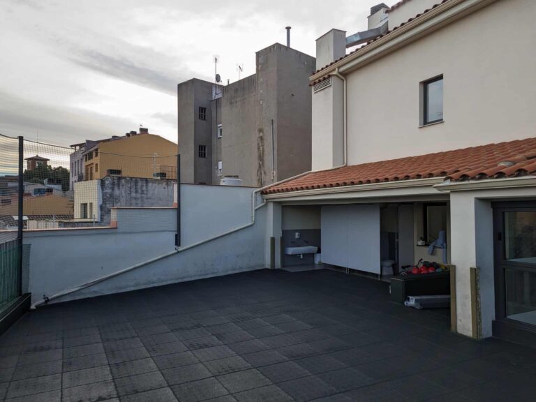 Patio exterior en terraza de la Escola La Mercè en Martorell con pavimento de caucho, porche y red perimetral.