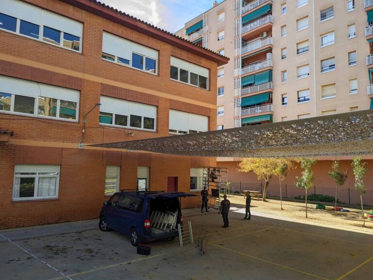 Instalación de malla de sombra tensada anclada a fachada en el patio de la Escola Les Planes en La Llagosta.
