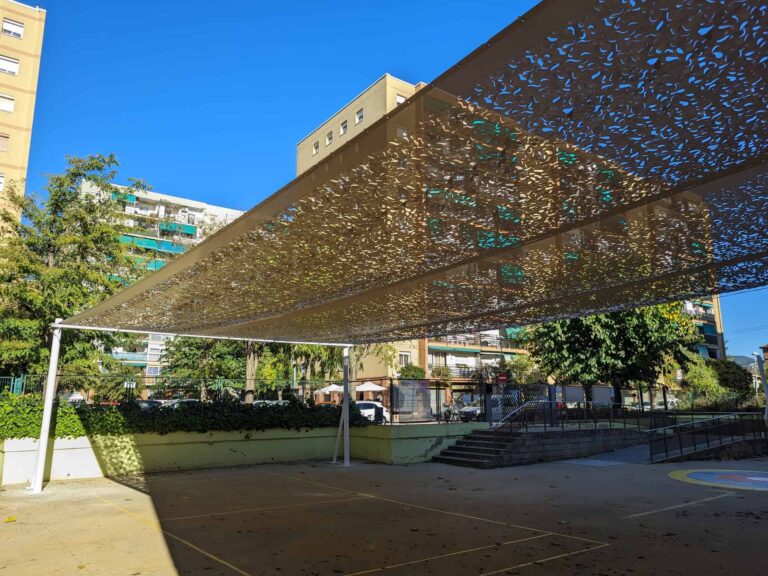 Toldo tensado con tejido microperforado sobre estructura metálica en el patio de la Escola Les Planes en La Llagosta.