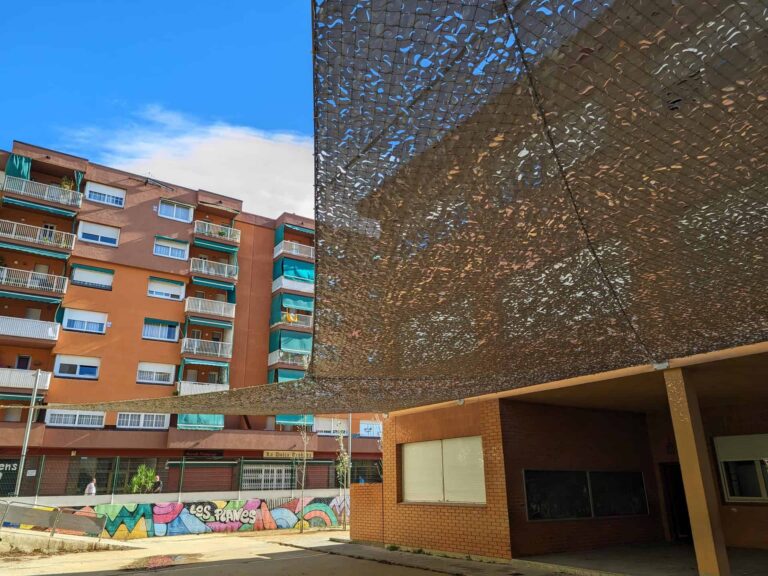 Malla de sombreo calada tensada sobre el patio de la Escola Les Planes en La Llagosta.