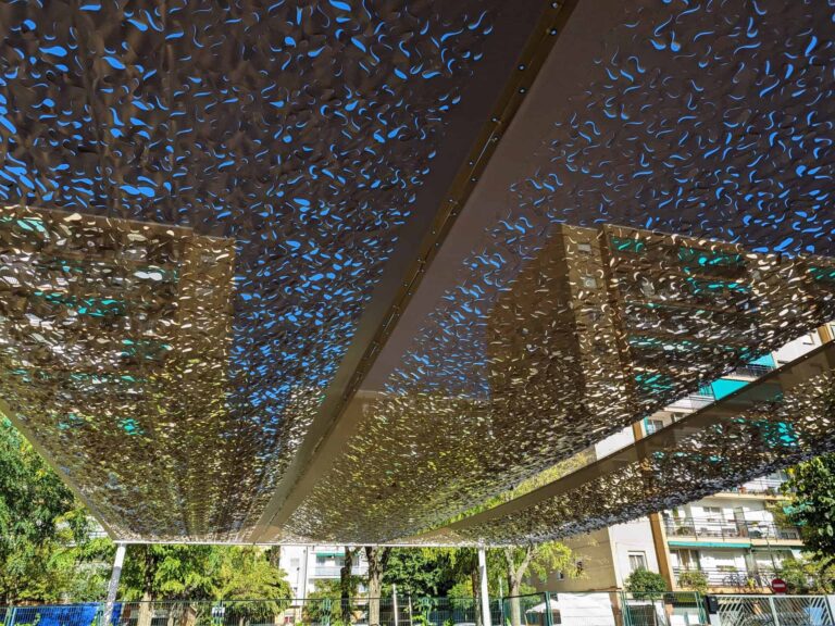 Vista inferior de estructura de sombra con paneles calados microperforados en el patio de la Escola Les Planes en La Llagosta.