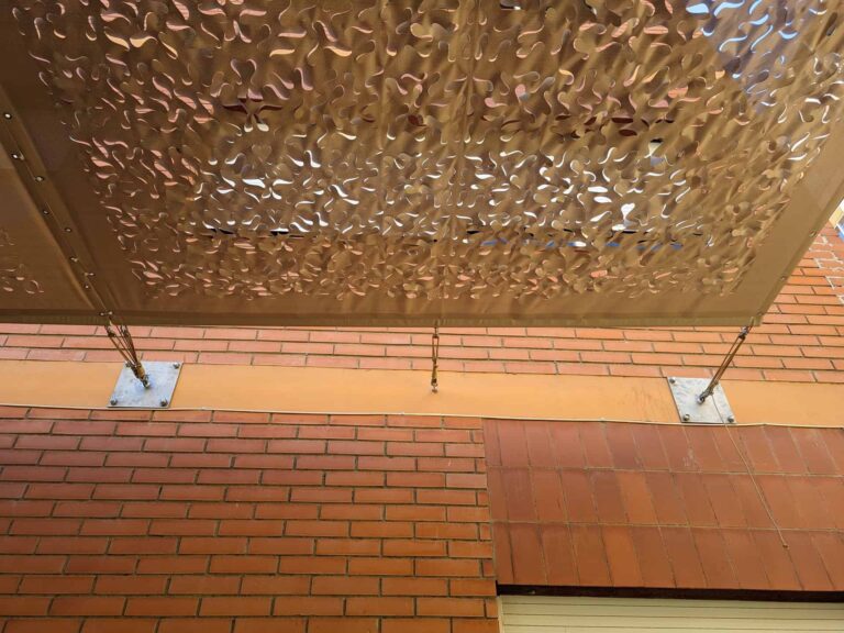 Detalle de anclaje a fachada de ladrillo y lona microperforada calada en la Escola Les Planes de La Llagosta.