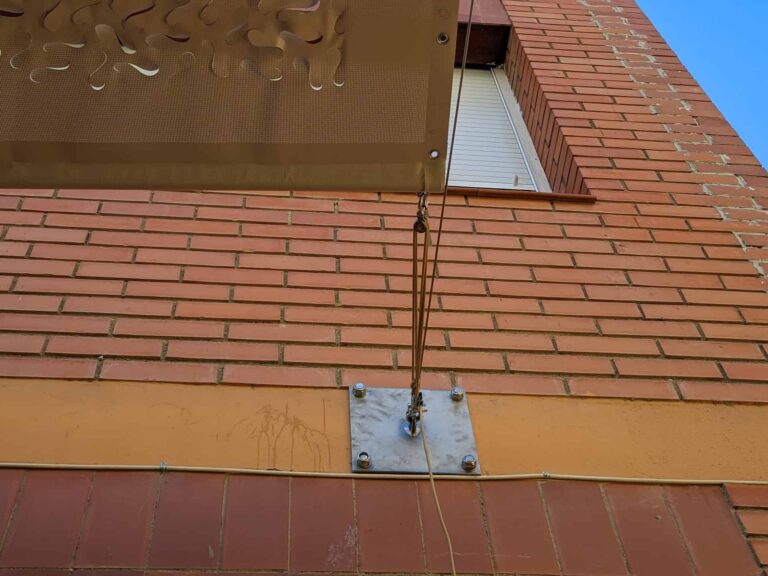 Detalle del anclaje y sistema de poleas de una vela tensada fijada a la fachada de ladrillo en Escola Les Planes.