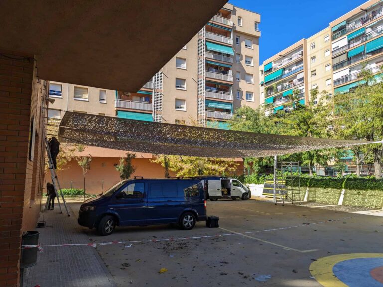 Instalación de una gran vela de sombra microperforada en el patio de la Escola Les Planes en La Llagosta.