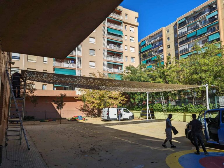 Instalación de vela de sombra calada anclada a fachada y postes en el patio de la Escola Les Planes en La Llagosta.