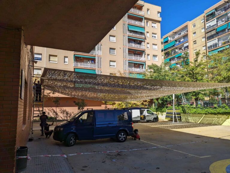 Instalación de una gran vela de sombra microperforada en el patio de la Escola Les Planes en La Llagosta.