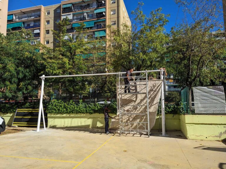 Montaje de estructura metálica blanca y tejido de sombra con andamio en el patio de la Escola Les Planes.