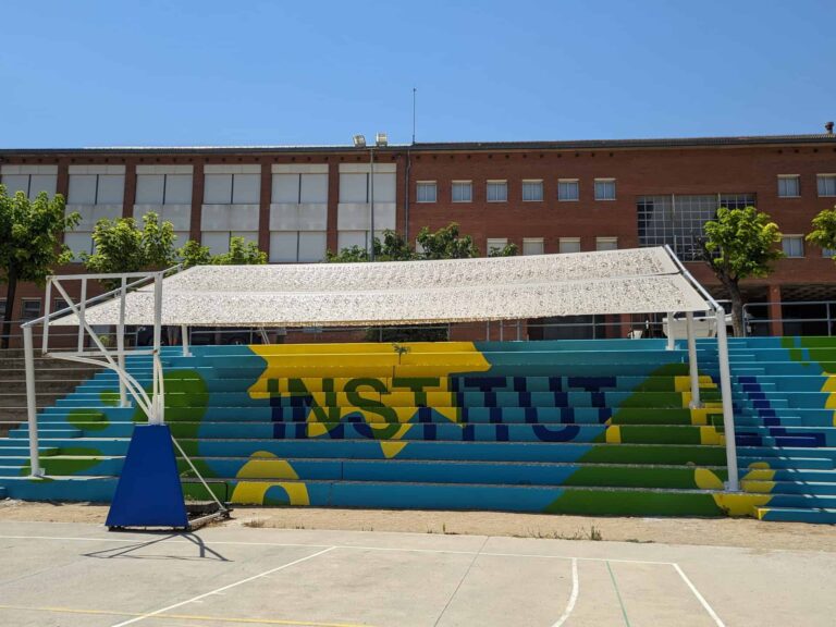 Estructura de sombra instalada sobre las gradas pintadas del patio del Institut El Cairat en Esparreguera.