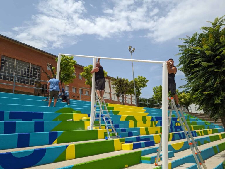Montaje de estructura metálica blanca para sombra sobre gradas pintadas en el Institut El Cairat de Esparreguera.