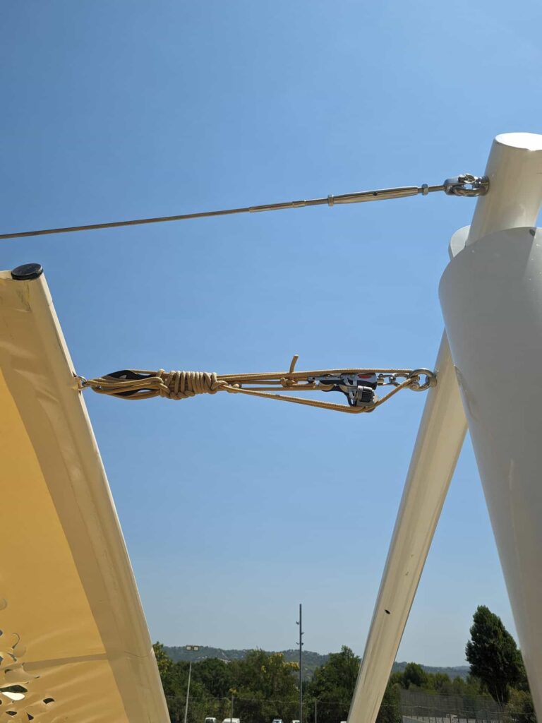 Detalle del sistema de poleas, cabo y tensor metálico fijados a un poste para vela tensada en Esparreguera.