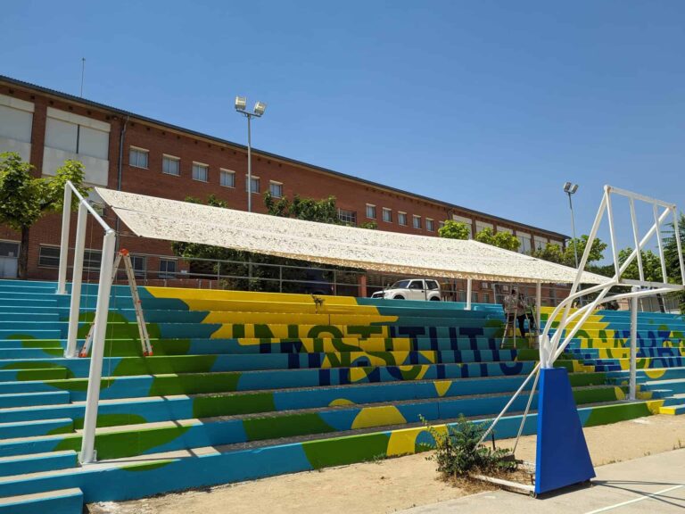 Estructura de sombra instalada sobre las gradas pintadas del patio del Institut El Cairat en Esparreguera.