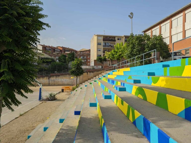 Gradas de hormigón pintadas con motivos coloridos en el patio exterior del Institut El Cairat en Esparreguera.