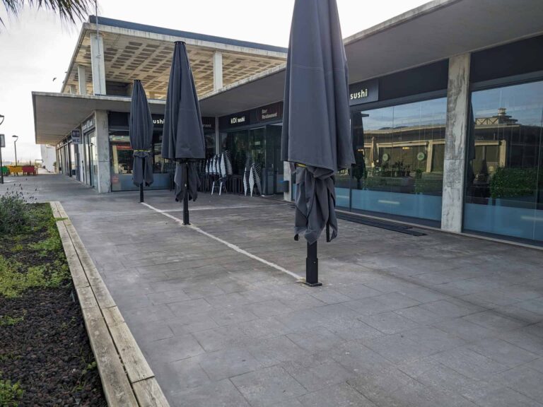 Fila de parasoles cerrados de color gris oscuro instalados en la terraza exterior del restaurante Koi Sushi en Port Premià.